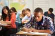 Male Pupil Studying At Desk In Classroom
