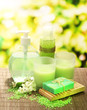 Cosmetics bottles and natural handmade soap on green background