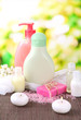 Cosmetics bottles and natural handmade soap on green background
