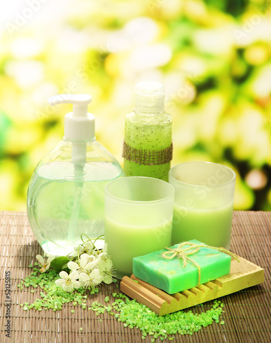 Photo: Cosmetics bottles and natural handmade soap on green background Cosmetics bottles and natural handmade soap on green background