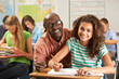 Teacher Helping Female Pupil Studying At Desk In Classroom