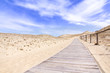 Wooden lane in the sand dunes with blue sky and clouds