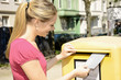 Junge Frau wirft Brief in Briefkasten