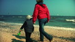 Mother and little boy running on the beach, slow motion