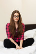 Cute young girl in glasses on the bed