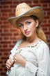 young woman with  straw hat and white kaftan against a brick wal