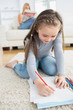 Little girl drawing sitting on floor with mother reading