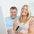 Couple using laptop on the sofa to shop online