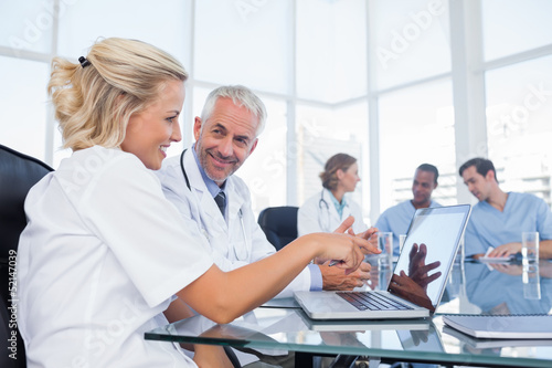 Photo: Two smiling doctors looking at a laptop Two smiling doctors looking at a laptop