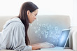 Photo: Woman using laptop with binary codes floating over Woman using laptop with binary codes floating over
