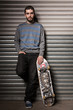Attractive skater leaning against metal shutters