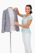 Fashion designer measuring blazer lapel on mannequin and smiling