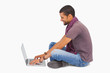 Photo: Man wearing scarf sitting on floor using laptop Man wearing scarf sitting on floor using laptop