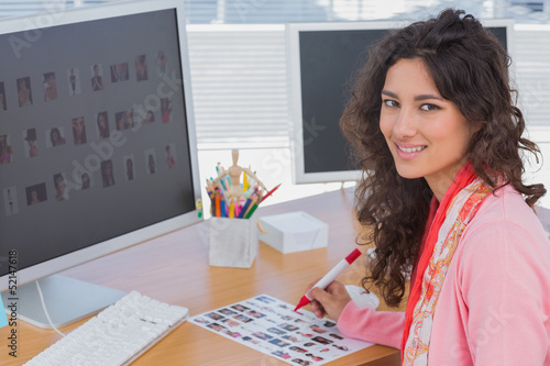 Photo: Editor marking the contact sheet and smiling at camera Editor marking the contact sheet and smiling at camera
