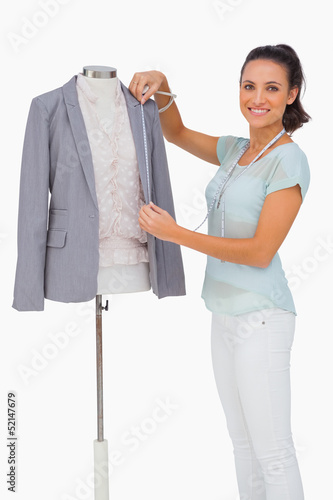 Photo: Fashion designer measuring blazer lapel on mannequin and smiling Fashion designer measuring blazer lapel on mannequin and smiling
