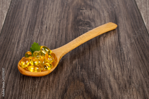 Photo: spoon full of tablets on wooden table spoon full of tablets on wooden table