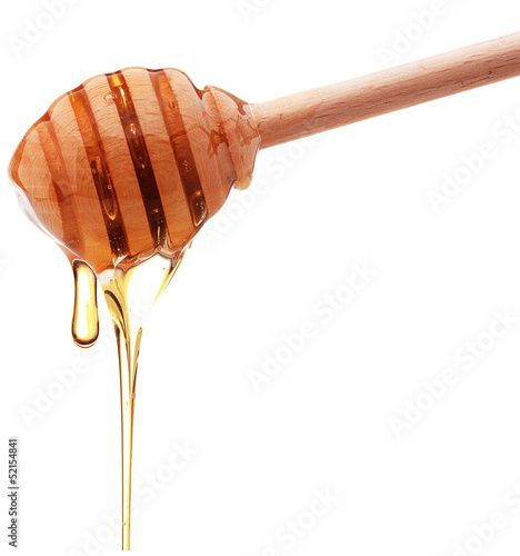 Photo: Honey dripping from a wooden honey dipper isolated on white back Honey dripping from a wooden honey dipper isolated on white back