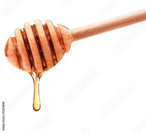 Photo: Honey dripping from a wooden honey dipper isolated on white back Honey dripping from a wooden honey dipper isolated on white back