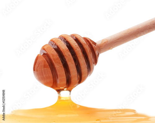 Photo: Honey dripping from a wooden honey dipper isolated on white back Honey dripping from a wooden honey dipper isolated on white back