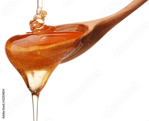 Photo: Honey dripping from a wooden honey dipper isolated on white back Honey dripping from a wooden honey dipper isolated on white back