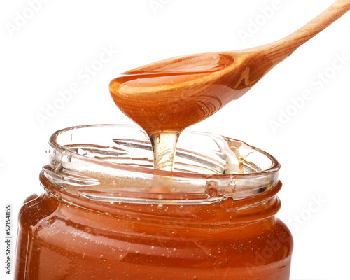 Photo: Honey dripping from a wooden honey dipper isolated on white back Honey dripping from a wooden honey dipper isolated on white back