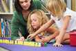 Elementary Pupils Counting With Teacher In Classroom