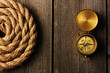Antique compass and rope over wooden background