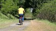 Adult man cycling on country road with puddles
