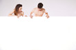 Man and woman looking behind white panel isolated on white backg