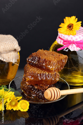 Photo: Jars of honey and honeycomb on black background Jars of honey and honeycomb on black background