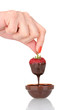 Hand holding strawberry in chocolate isolated on white
