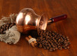 Coffee pot with coffee beans on brown wooden background