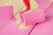 Paint roller brush with pink paint, on wooden background