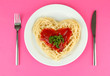 Cooked spaghetti carefully arranged in  heart shape and topped