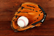 Baseball glove and ball on wooden background