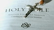 Rosary beads falling onto first page of the holy bible