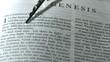 Rosary beads falling onto book of genesis