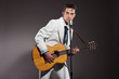 Retro rock and roll singer with guitar wearing white suit. Studi