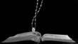 Rosary beads falling onto open bible
