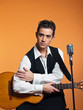 Retro country singer with guitar wearing black suit. Studio shot