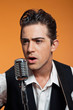 Retro country singer with guitar wearing black suit. Studio shot
