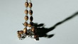 Rosary beads casting a shadow and then falling on white surface