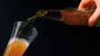Hand pouring bottle of beer into glass on black background