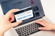 Woman's hand holding a bank card over a laptop.