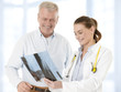 Female doctor talking with senior patient and showing her x-ray