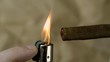 Hand lighting a cigar on beige background