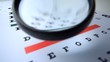 Magnifying glass falling onto eye test close up