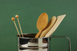 wooden kitchenware in metal jug  on old wooden table over green