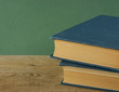 Old books on a wooden shelf against a green wall