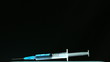 Syringe of blue liquid falling and bouncing on black surface
